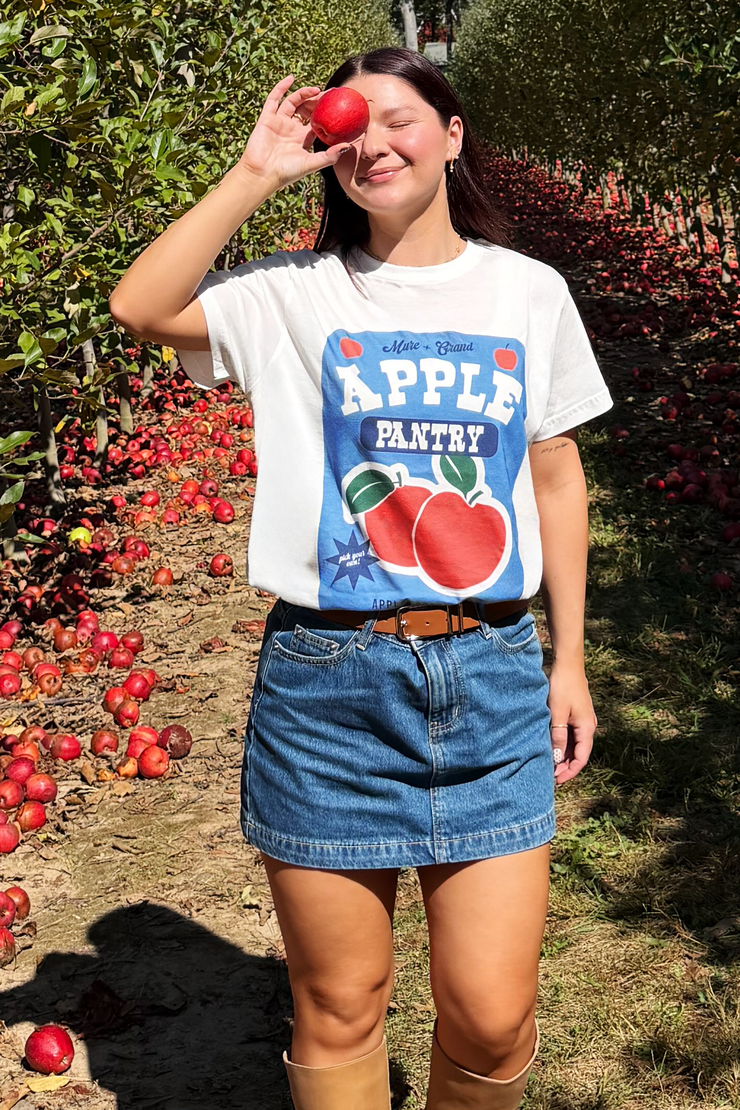 Person wearing a 'Apple Pantry' t-shirt in an apple orchard
